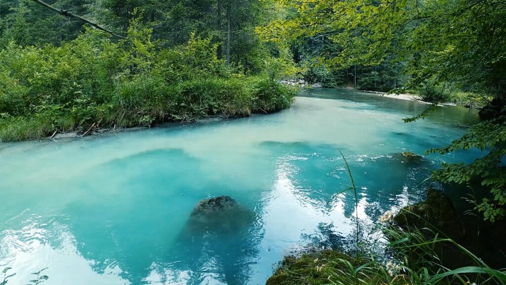 Pristine turquoise river flowing through a serene, forested landscape enhances tranquility and natural beauty. amor por la naturaleza